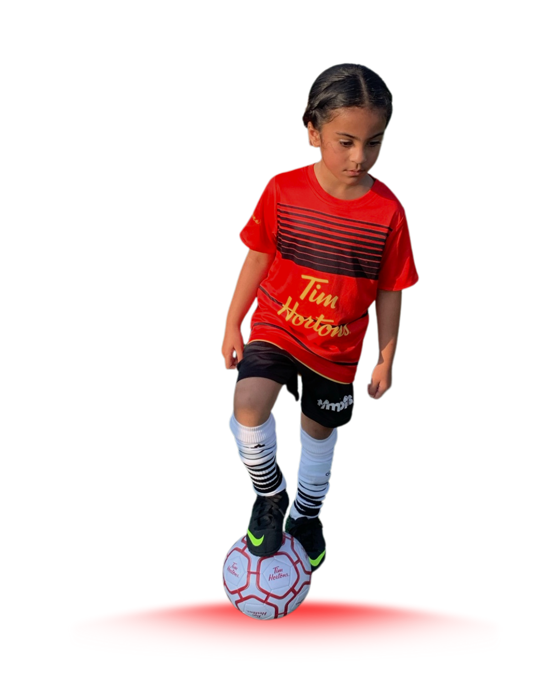 Image of a young girl wearing a red soccer uniform with her right foot resting on the ball